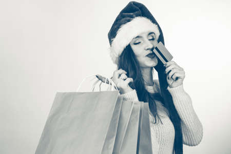 Happy girl on christmas shopping. Young cheerful woman with bags wearing santa cap. Holidays celebration commerce happiness leisure concept. の写真素材