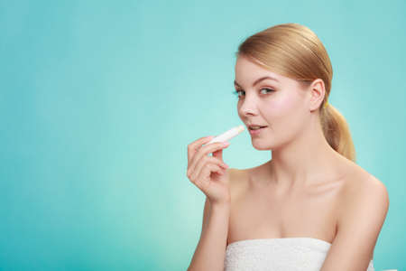 Female putting applying lip balm moisturizing balsam. Girl taking care of lips. Skincare.の写真素材