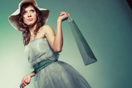 Stylish young woman love shop. Happy with new clothes Girl in green blue light dress and hat hold shopping bag.の写真素材