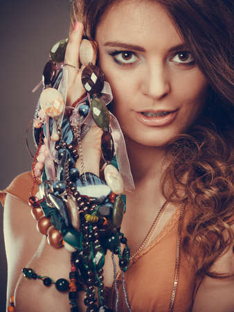 pretty young woman wearing bracelets and rings holding many plentiful of precious jewelry necklaces beads.の写真素材