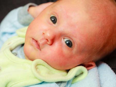 Little newborn baby in pyjamas lying on back. Face expression. Family, parenthood, childhood concept.の写真素材