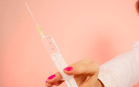 Injection concept. Close up hand of female doctor with big syringe. Medical help for disease.の写真素材