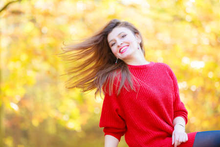 Relaxation and free time. Beauty modern girl in red rest on fresh air in autumn. Lovely attractive woman relax outdoor surrounded by trees and autumnal leaves.の写真素材