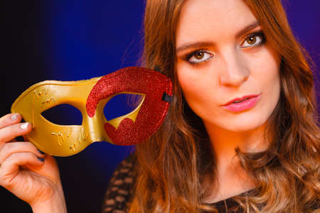 People celebration concept. Masquerade. Beautiful girl holding carnival mysterious mask on dark