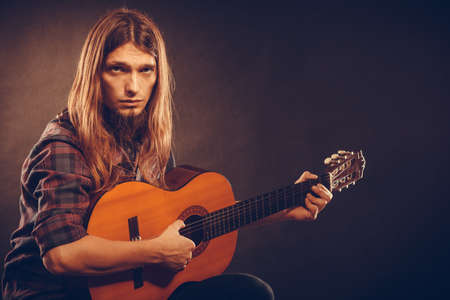 Guitarist trying out chords. Young male musican practicing on guitar. Music instrument passion concept.の写真素材