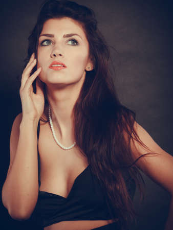 Party celebration concept.  Magnificent long hair woman red lipstick wearing black evening dress pearls necklace on darkの写真素材