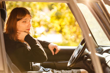 Fresh driver, traveling concept. Young man wearing sweater having long hair driving car carefully on...