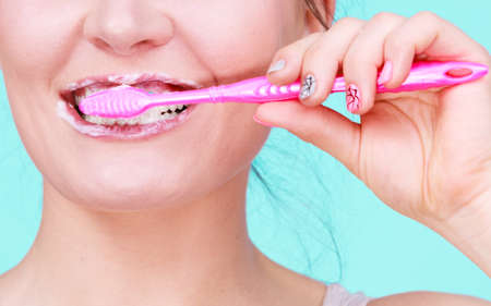 Woman brushing cleaning teeth. Girl with toothbrush close up. Oral hygiene. Blue green backgroundの写真素材