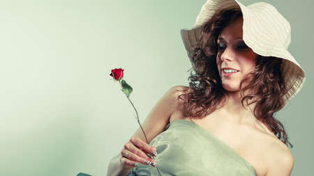 Romantic date gift nature loving young woman. Girl in light green dress hold small red rose.の写真素材