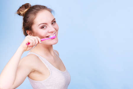 Woman brushing cleaning teeth. Girl with toothbrush. Oral hygiene. Blue backgroundの写真素材