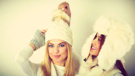 Fashion models people concept. Two women with winter clothes. Blonde and mixed race ladies wearing warm clothing.の写真素材