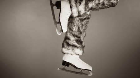 Woman legs wearing skates fur warm socks. Girl getting ready for ice skating. Winter sport activity. Studio shot b&w photoの写真素材