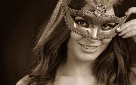Holidays, people and celebration concept. Closeup woman face with carnival venetian mask on dark...