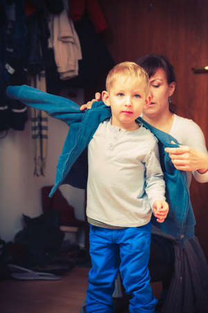 Parenting, taking care of child concept. Mother dressing up her son in winter clothes before going outの写真素材