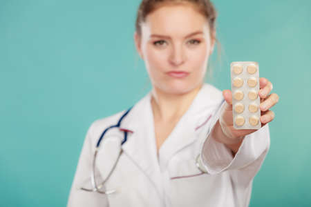 Ways of treatment. Pharmacist doctor in white medical unform apron showing pills. Woman specialist with stethoscope holding medication.の写真素材