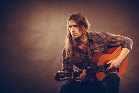 Hobby passion concept. Guitarist is playing the guitar. Long haired performer and his instrument.の写真素材