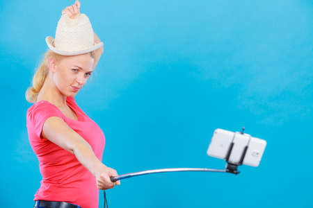 Technology, modern photography, confidence conept. Happy attractive adult blonde woman with sun hat...