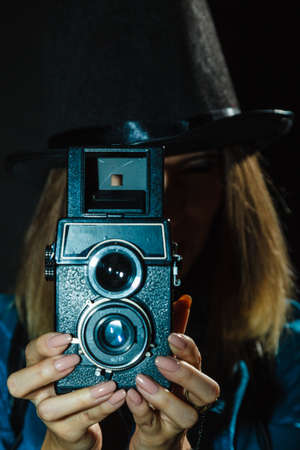 Photography and retro style. Young vintage attractive girl holds old aged camera. Steampunk photographer taking photo.の写真素材