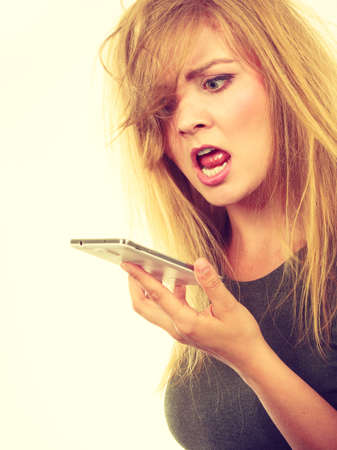 Unpleasant conversation, bad relationships concept. Screaming furiously angry young blonde woman talking on phoneの写真素材