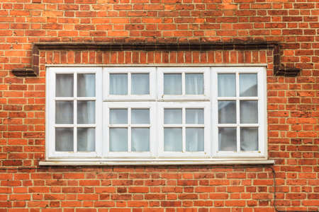 English architecture, structure on buildings concept. Red brick wall with white window