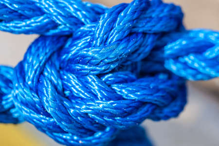 Shipping objects concept. Blue strong sailing ropes tied with knot. Outdoor shot on sunny day.
