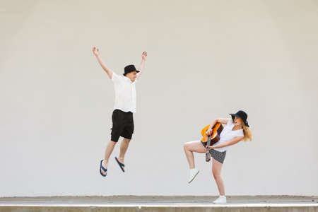 Relationship goals concept. Couple on romantic date. Woman playing guitar, man jumping next to herの写真素材