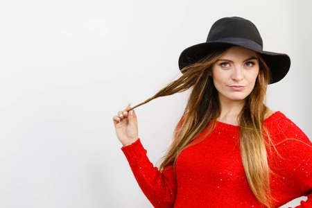 Fashion headwear clothing fun concept. Lady playing with hairs. Elegant girl wearing fashionable hat twisting her hair rolling it on finger.の写真素材