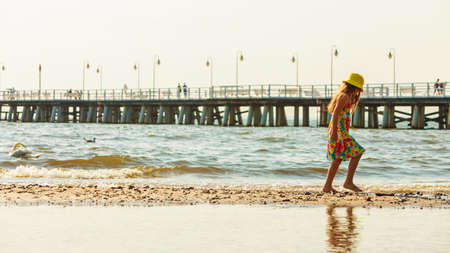 Joy and fun. Lovely little girl wearing summer clothes having fun outside on beach seaside. Child spending time playing near to sea ocean.の写真素材