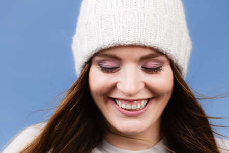 Attractive happy smiling woman long hair girl in winter wool cap studio shot on blue.の写真素材