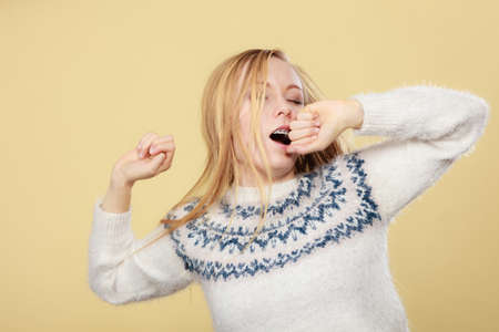 Tiredness, too much work at school concept. Sleepy yawning blonde teenage woman in jumper feeling exhaustedの写真素材
