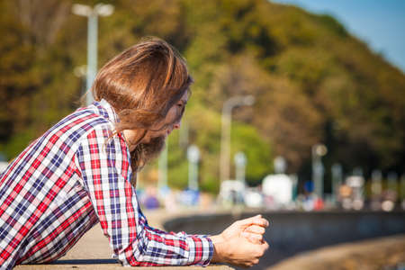 Man long hair alone on sea shore, lost in thought, is concerned and stressed about events in his life. Unemployment depression conceptの写真素材
