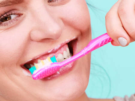 Woman brushing cleaning teeth. Girl with toothbrush close up. Oral hygiene. Blue green backgroundの写真素材