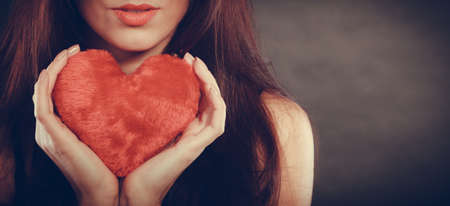 Woman long hair young female holding red heart love symbol studio shot on black. Valentines day happiness conceptの写真素材