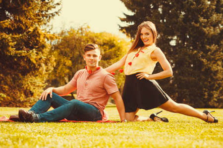 Love romance relationship valentines dating concept. Couple spending time together in park. Young girl and boy hugging on grass.の写真素材