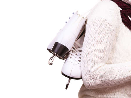 Woman carrying a pair of ice skates getting ready for ice skating, winter sport activity. Side view isolated on whiteの写真素材