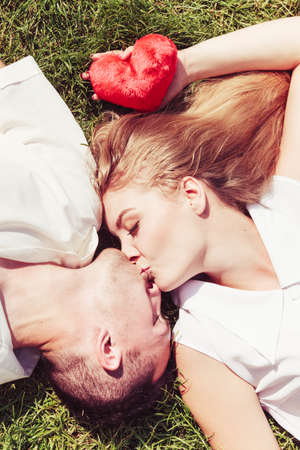 Relationship goals, love forever concept. Man and woman lying on grass and kissing, enjoying...