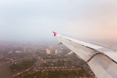 Adventure, travel, transport concept. View from plane window at sky with clouds, wing and cityの写真素材