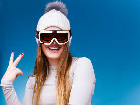 Attractive woman in winter cap gray sports thermal underwear for skiing training ski googles studio shot on blue.の写真素材