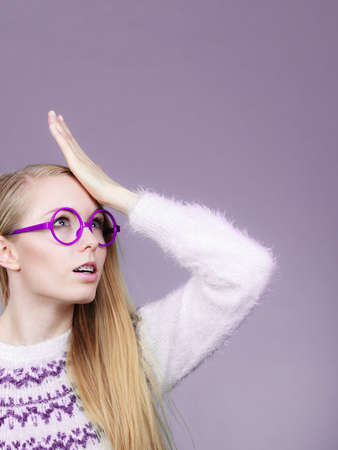 Face expressions, disregard, stupid behavior concept. Nerd blonde woman holding hand on forehead.の写真素材