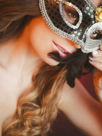 Holidays, people and celebration concept. Closeup woman face with carnival venetian mask on dark background.の写真素材