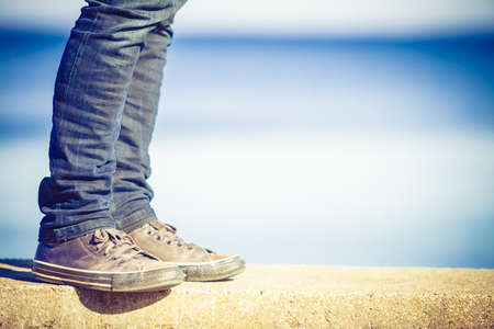 Male legs wearing denim trousers sneakers casual style walking relax by seaside at summer sunny