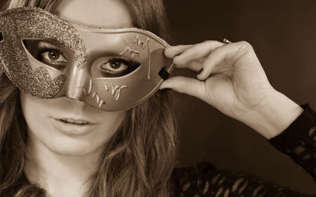 Holidays, people and celebration concept. Closeup woman face with carnival venetian mask on dark...