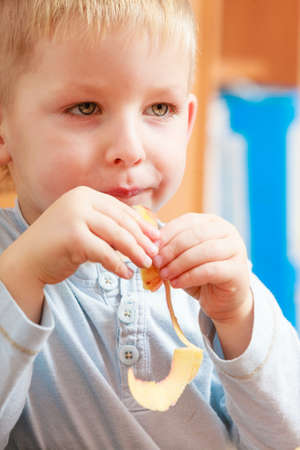 Morning routine in family, healthy diet for children concept. Little boy eating apple for snackの写真素材
