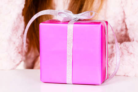 Closeup of female model with pink gift box silver ribbon, girl with christmas present. Birthday, holidays surprise.の写真素材
