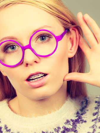 Rumors, gossip and gestures concept. Nerdy blonde woman listening carefully with hand close to earの写真素材