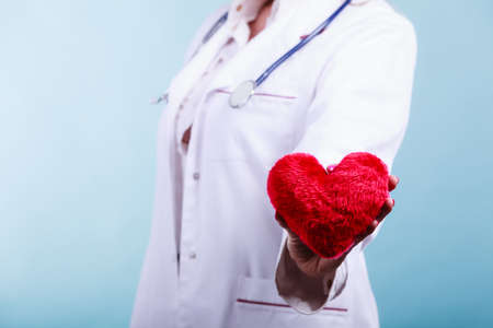 Love from working and helping people. Part body female doctor in white medical apron with heart on blue. Enjoy work concept.の写真素材