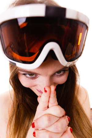 Fun, folly concept. Woman hiding her face behind hands with with red painted nails wearing big ski goggles on her head, crazy closeup.の写真素材