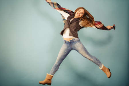 Fun and fashion concept. Woman fashionable casual style autumn girl jumping, flying in air on blue