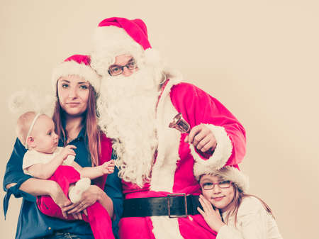 Christmas family concept. Mother, toddler girl, baby, and man wearing Santa Claus costume.の写真素材