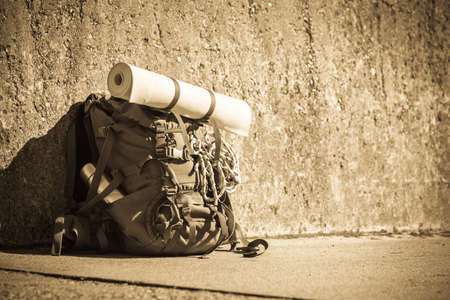 Hiking backpack camping and mountain exploring tourist equipment outdoor on grunge wall. Adventure,...